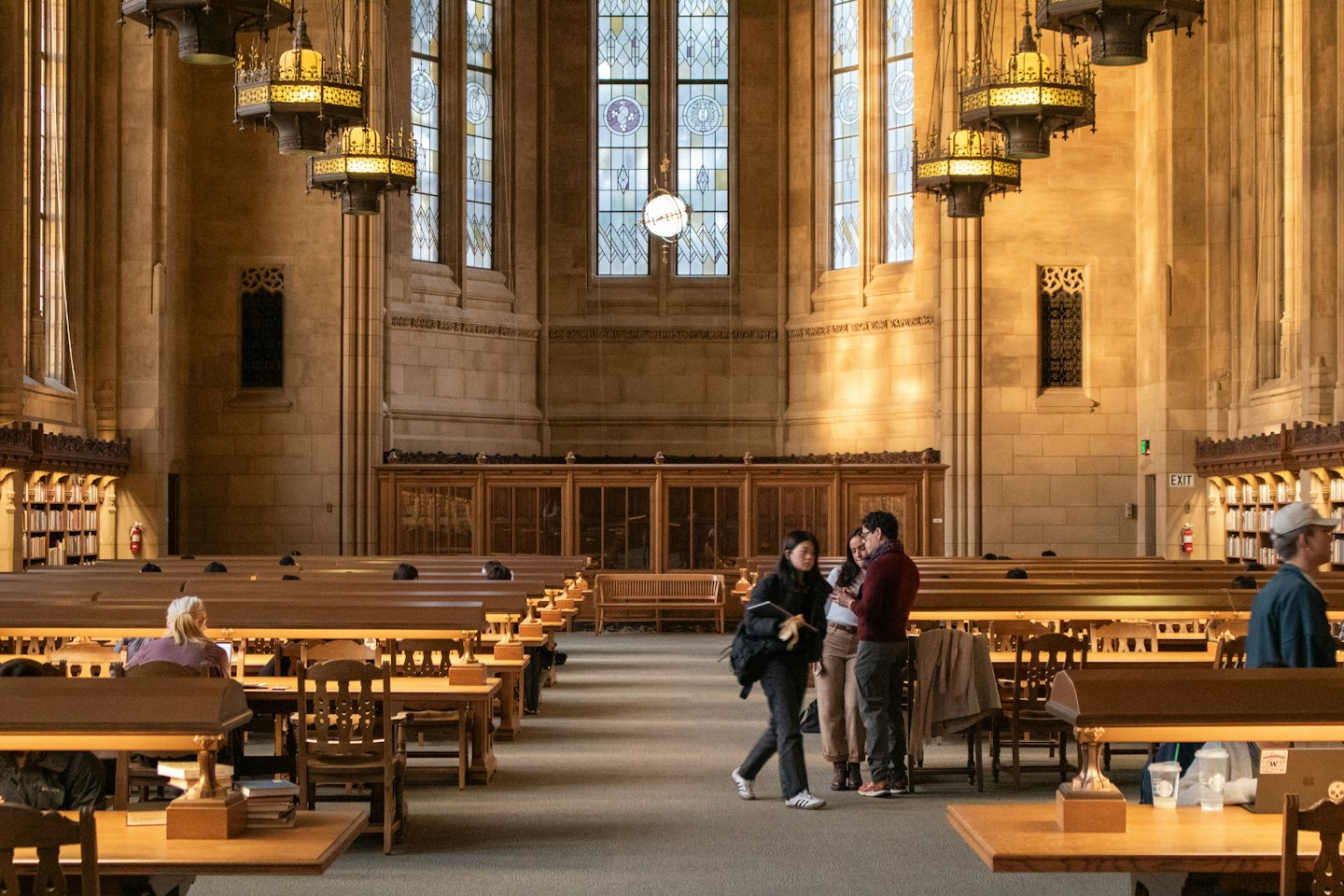 Students study and talk in a grand historic library reading room.