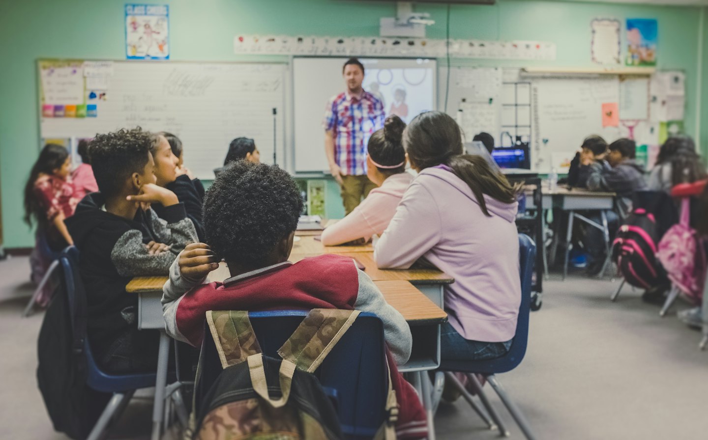 Students paying attention to a teacher in a classroom.